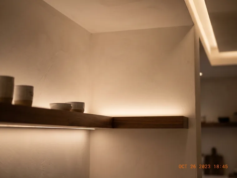 Warm LED tape and linear cove lighting along a shelf and ceiling